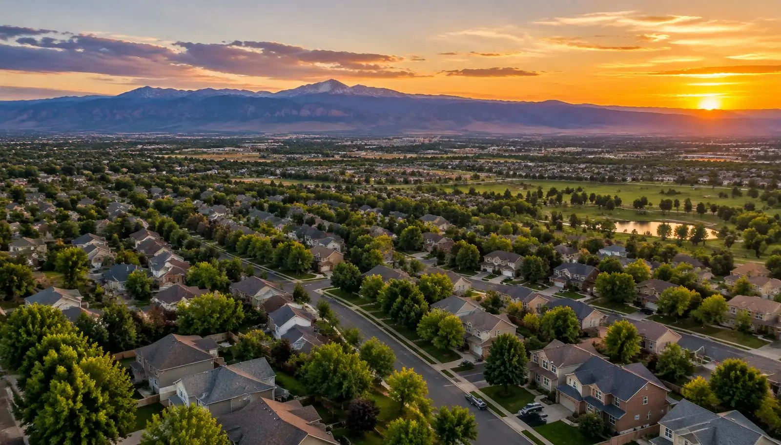 Aerial view of Denver metro neighborhoods with the Rocky Mountains at sunset